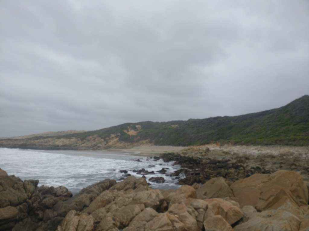 A rocky sea shore. A sandy beack is visible in the distance. The house at Fonteintjies is out of sight to the far right.