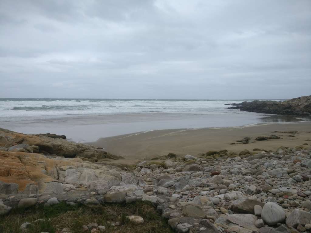 A rocky shore, a sandy beach, and the ocean.