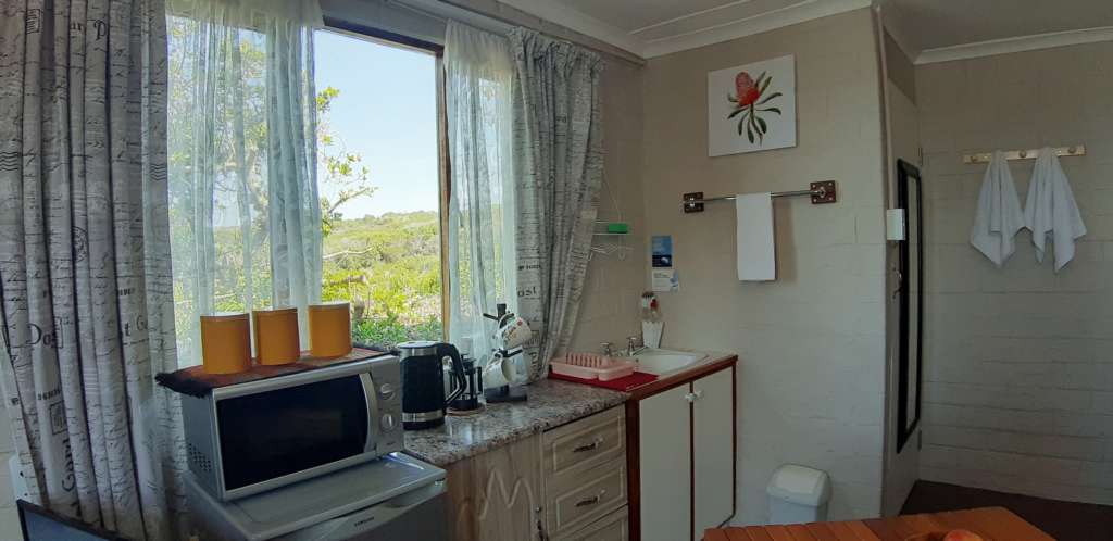 Kitchenette in the annex room at Fonteintjies. There is a small fridge with a microwave oven on top, a cupboard unit with a kettle and coffee plunger on top, and a small hand basin.
