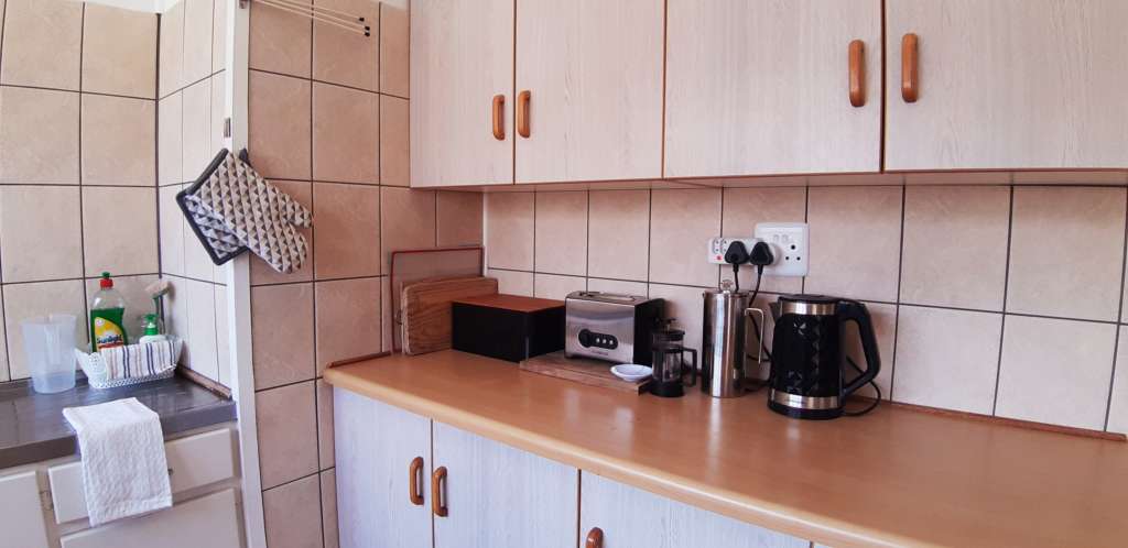 The kitchen at Fonteintjies, focusing on a counter top. There are cutting boards, a bread bin, a toaster, a kettle, and a coffee plunger.