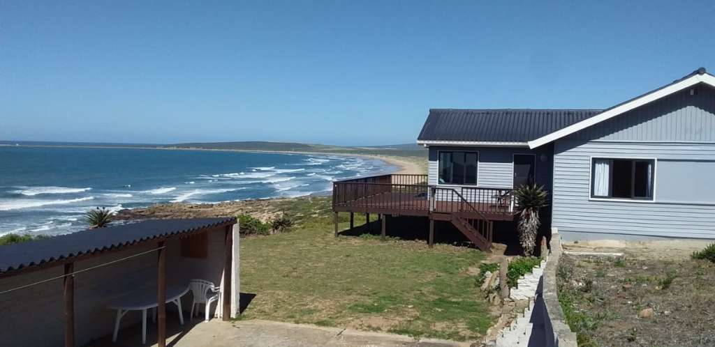 Die Fonteintjies-huis en dek vanaf die tuin gesien, met die see daarbuite. Die patio-area is aan die linkerkant.